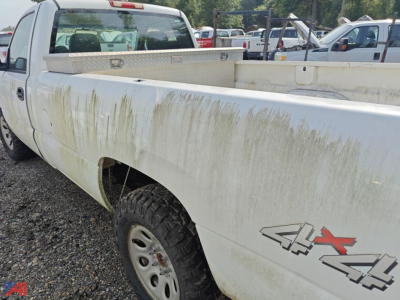 Truck bed of a white 2006 GMC Sierra 1500 pickup showing dirt splatter and 4x4 decal on rear fender, utility bed in background.