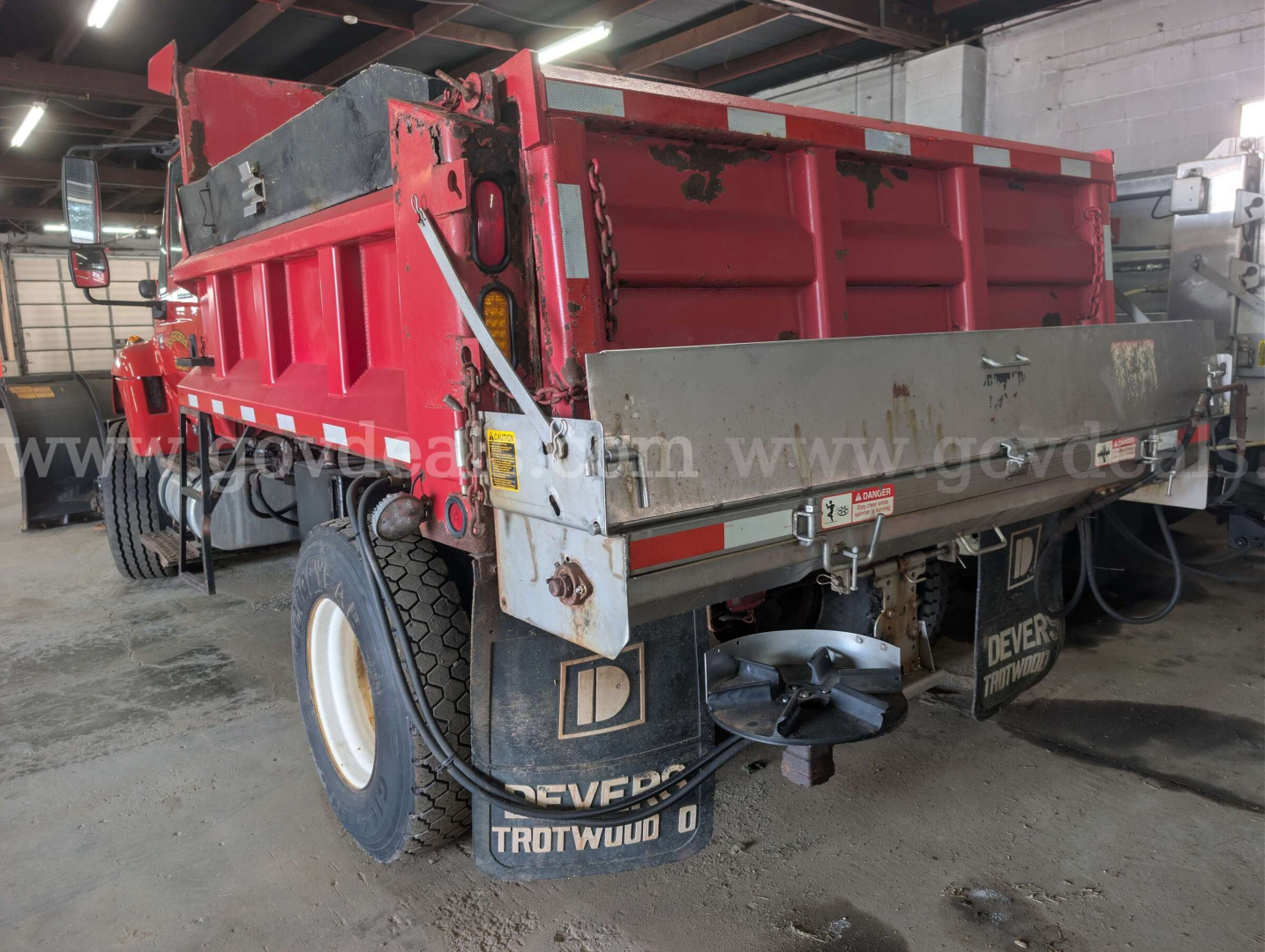 Dump truck bed and rear view of a 2006 International 7400 dump truck showing red dump body, rear tailgate, bumper, and mud flaps.