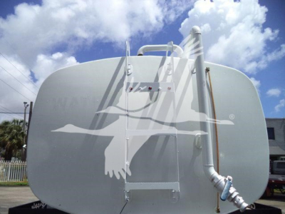 Tank trailer in side view with rounded front, top manway, piping, and ladder. No legible model text visible on tank.