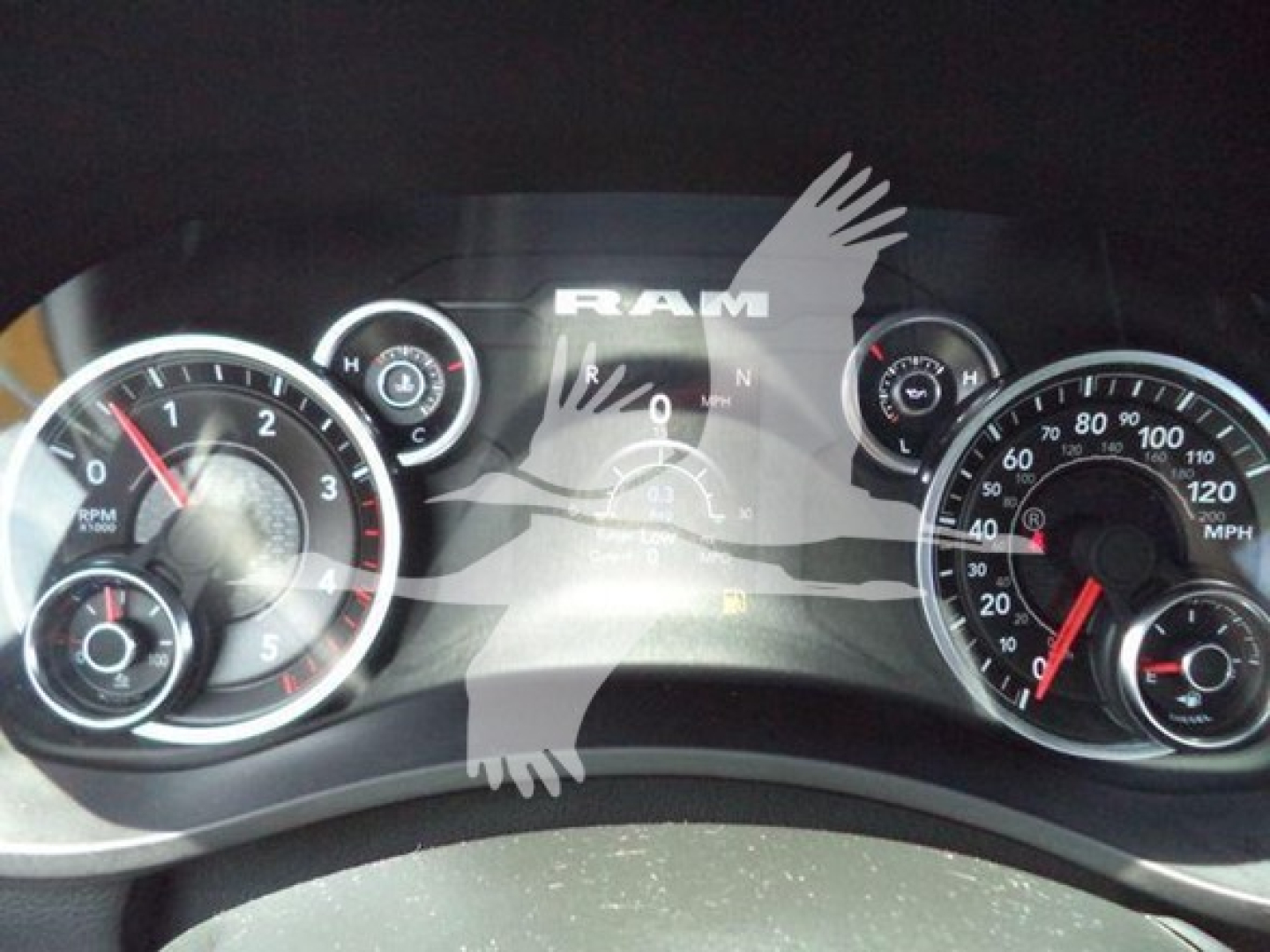 Ram dashboard showing speedometer and tachometer with 'RAM' logo and gear indicator in center cluster.