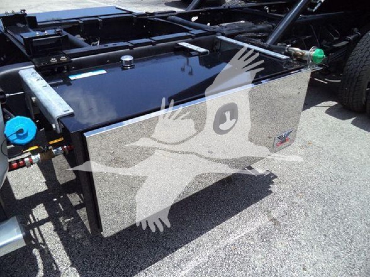 Ram 5500 rollback truck chassis showing a glossy aluminum toolbox/storage box mounted near the cab with blue and green fittings on either side.