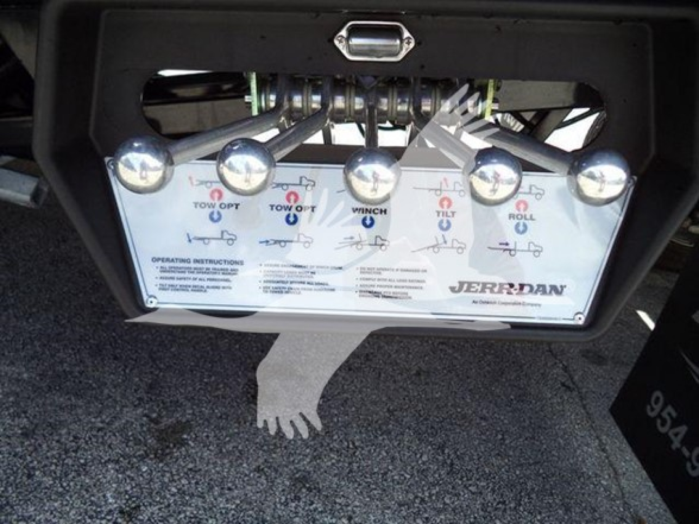 Ram 5500 rollback tow plate with joystick and control diagram showing labels; Jerr-Dan branding; components and chrome pins visible under rear bumper.