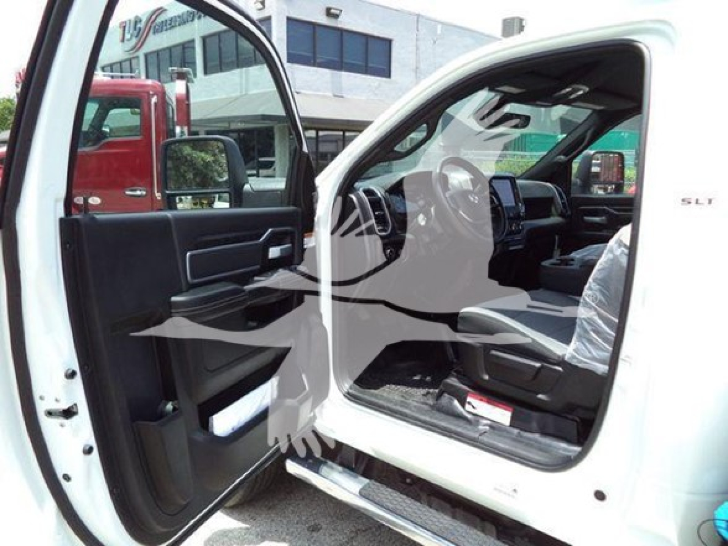 Ram 5500 SLT interior and open driver door showing steering wheel, dashboard, and front seating from a truck dealership, with SLT badge on door.