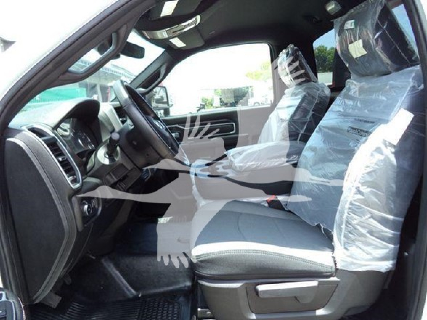 Ram 5500 SLT interior view showing front seats wrapped in protective plastic, steering wheel, dashboard, and driver-side door.