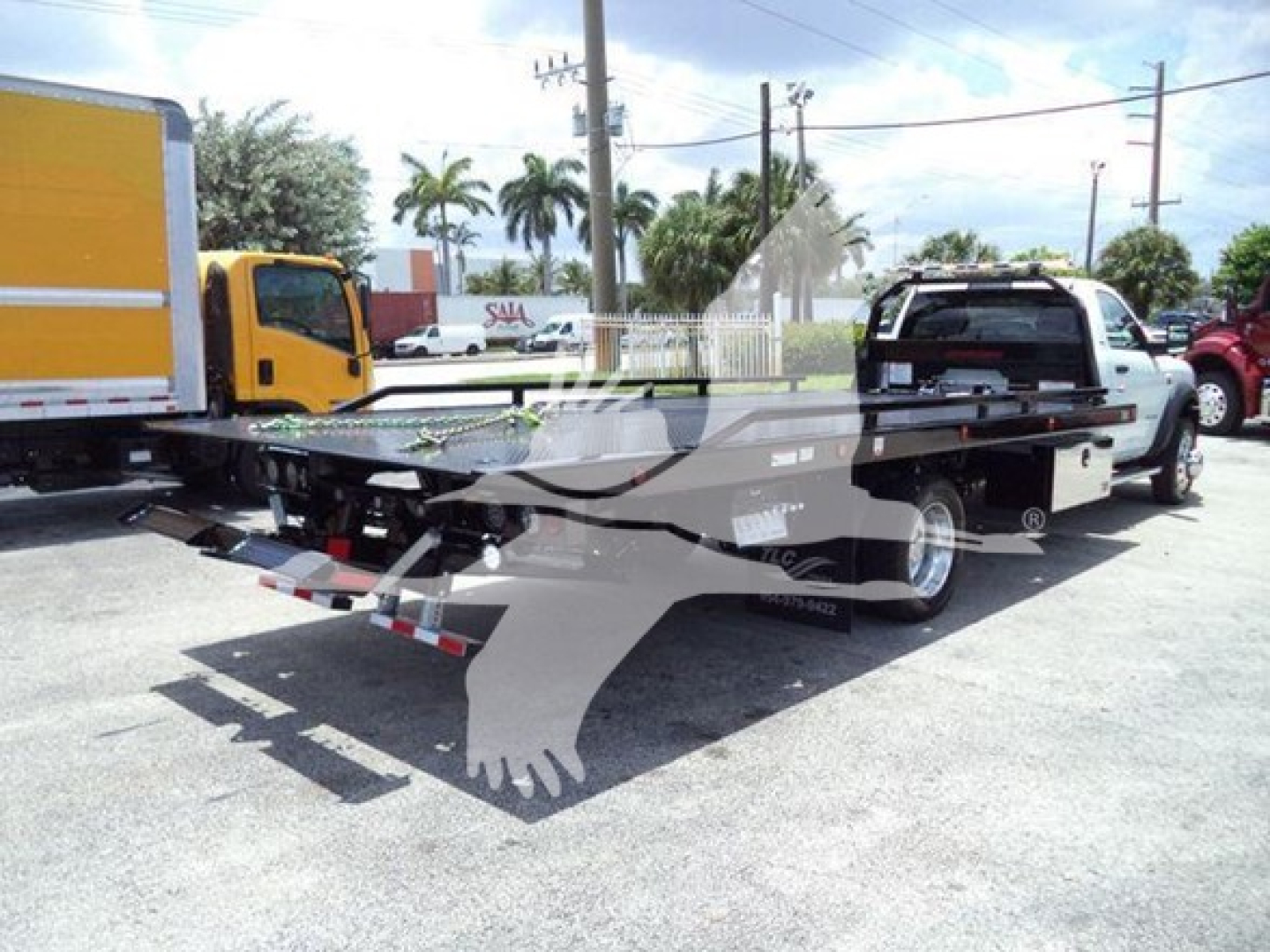 Ram 5500 SLT rollback tow truck showing flatbed and rear hitch with branding and vehicle outline overlay.
