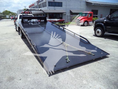 Ram 5500 rollback truck flatbed with winch chains and tie-downs on a black diamond plate bed