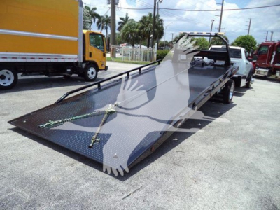 Ram 5500 rollback tow truck bed on a trailer showing a lowered steel platform with tie-down chains.