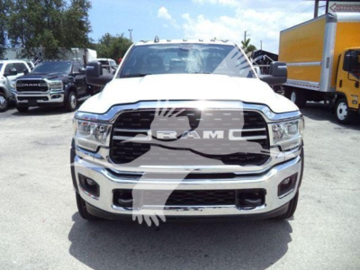 Front view of a white 2024 Ram 5500 SLT pickup truck in a lot; prominent Ram grille with RAM letters; big bumper with chrome accents; other trucks in background.