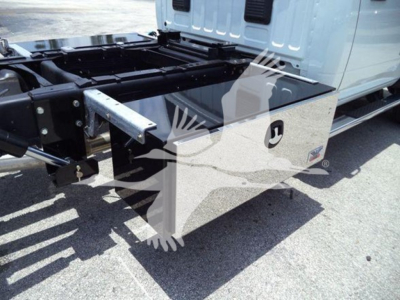 Truck bed toolbox on a 2024 Ram 5500 SLT rollback truck showing a silver aluminum toolbox mounted under the cab with hydraulic lines and frame in background.