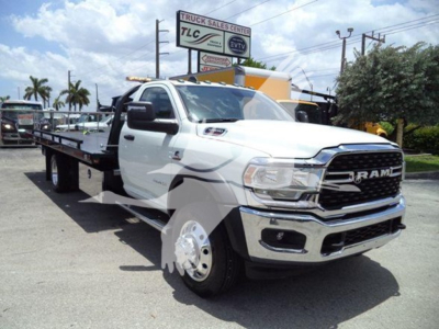 Ram 5500 rollback tow truck white with long flatbed, front grille RAM logo, chrome bumper, dual rear wheel configuration, side view mirrors, VIN sticker area not visible