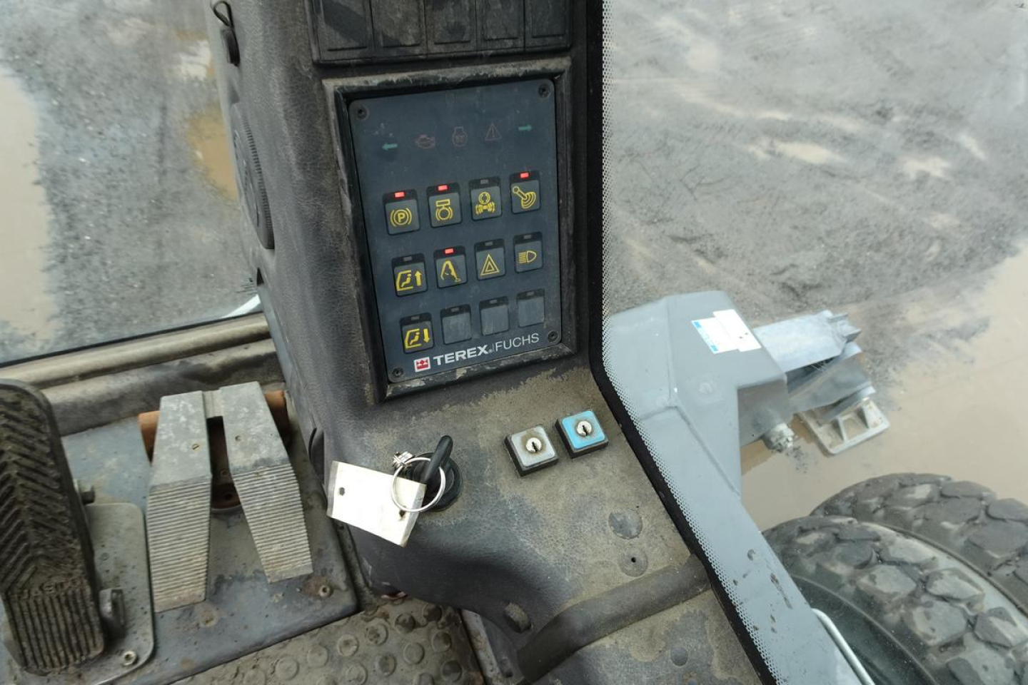 Control panel of a Terex MHL 331 with multiple colored push buttons and switches, key in ignition, display reading model branding 'TEREX FUCHS' and lock.