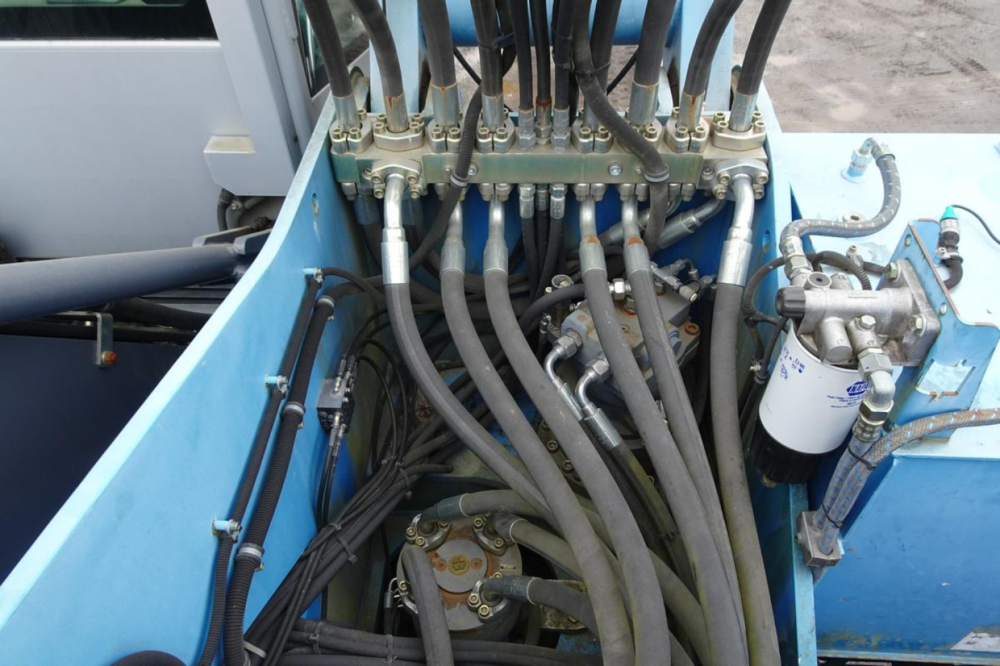 Hydraulic hoses and control valves on a Terex MHL 331 boom truck. Visible hydraulic manifold, hoses, filter, and fittings in a blue chassis compartment.