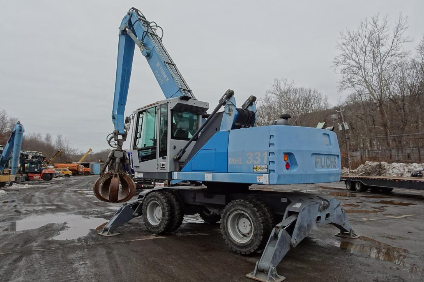 Terex MHL 331 material handler/crane in blue, side view showing articulated arm and grapple, identification numbers visible.