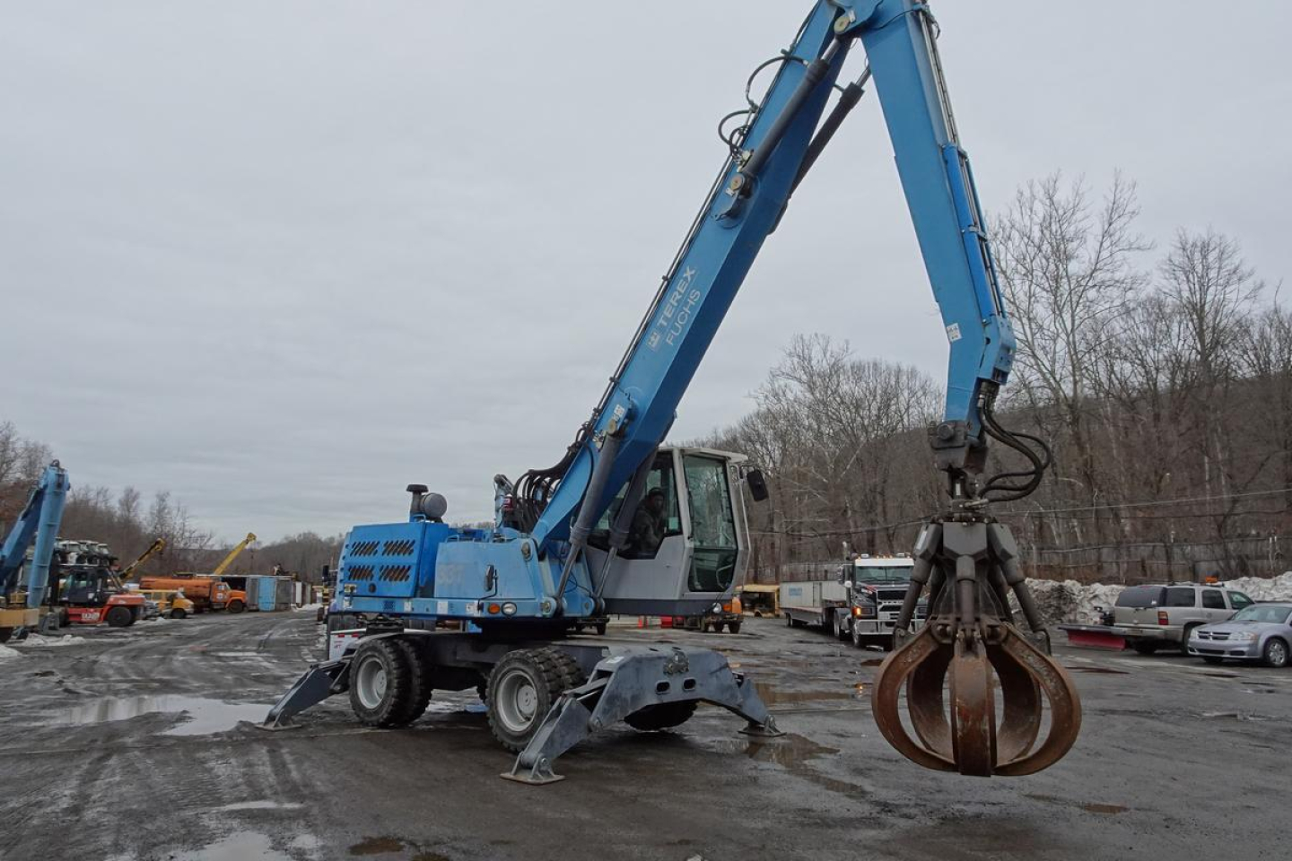 Terex MHL 331 rough terrain material handler in blue with a claw/grapple attachment, operating at a used equipment lot.