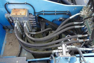 Hydraulic control valves and hoses in a Terex MHL 331 utility crane; hydraulic lines and a control valve block visible in the engine bay area.