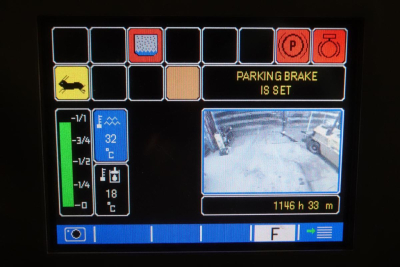 Screen showing status indicators and a small live feed; parking brake indicator lit; blue panels show numbers and temperature; right panel shows a snowy scene, distance 1146 h 33 m.