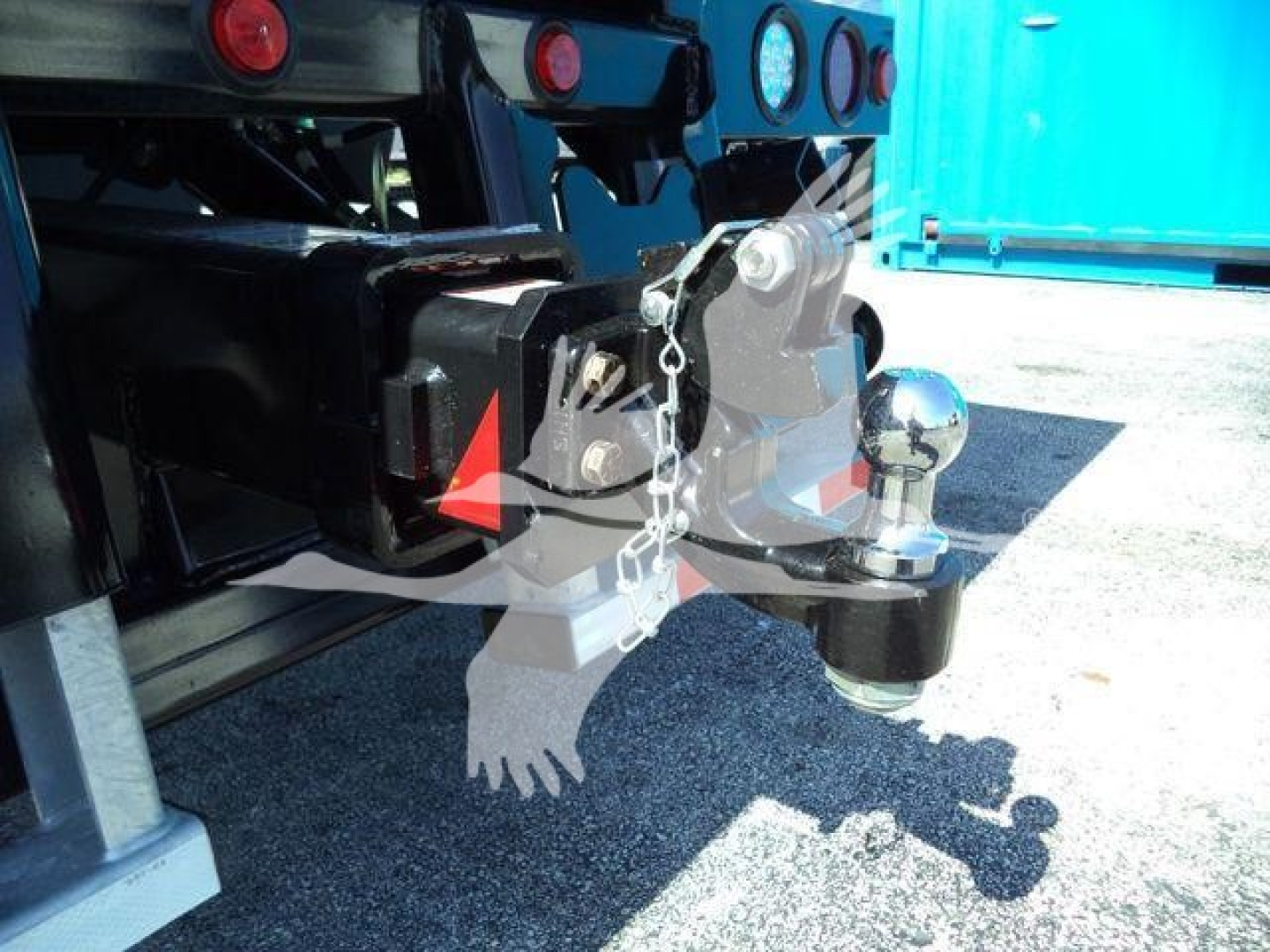 Tow hitch and rear bumper area of a 2026 Kenworth T880 truck showing hitch receiver, safety chain, ball mount, and rear bumper with lights.