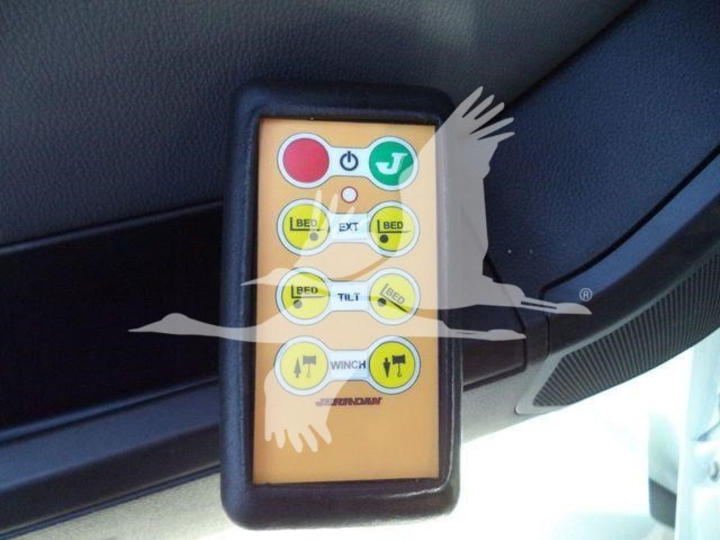 Kenworth T880 rollback truck control pendant showing buttons labeled red stop, green start, tilt, winch, and lift with yellow/black icons.