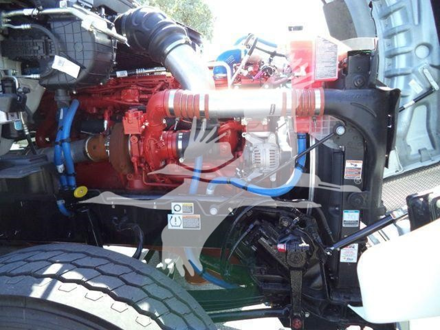 Kenworth T880 engine bay showing red diesel engine and blue hoses in a rollback truck.