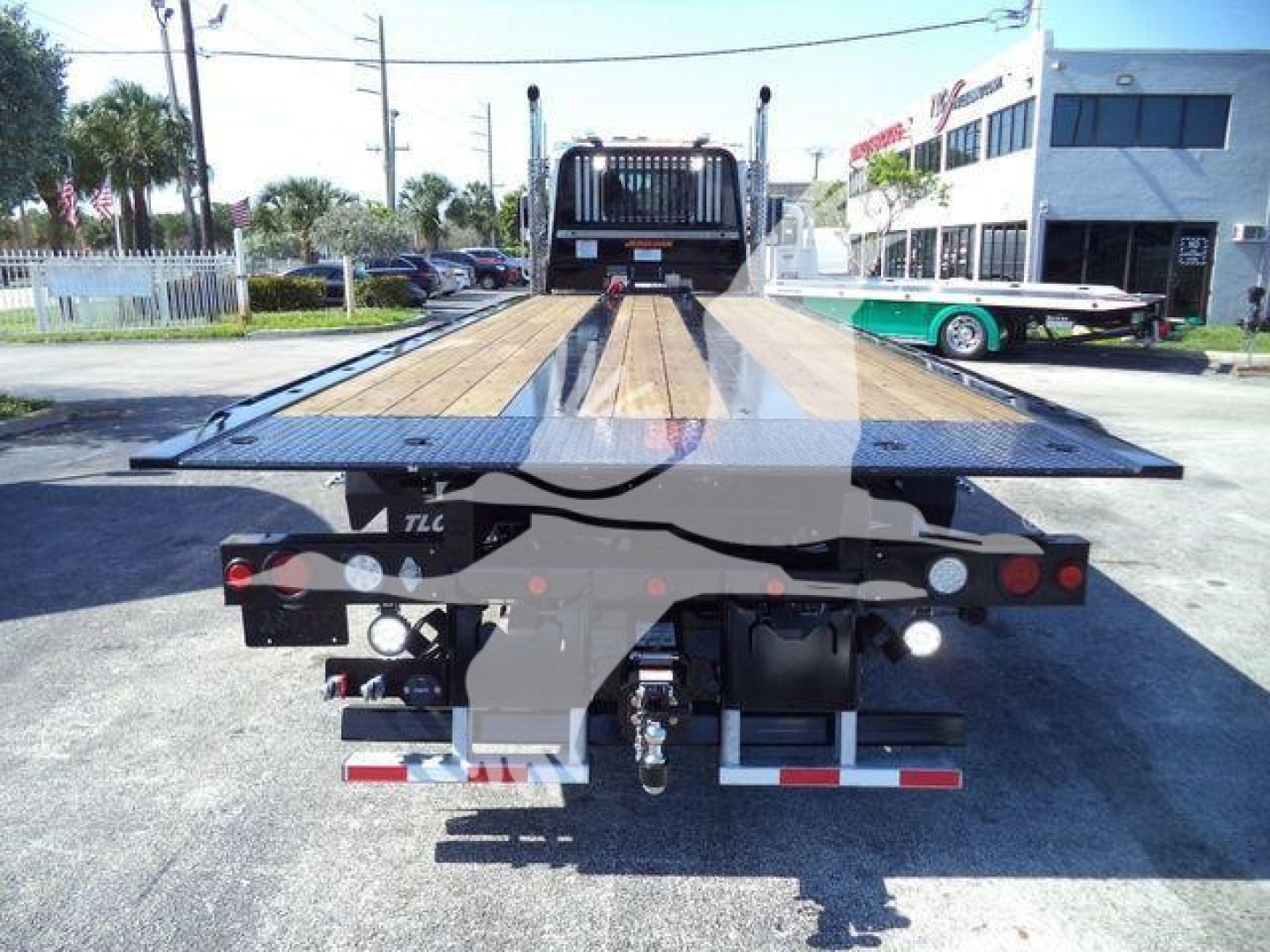 Kenworth T880 rollback truck rear view showing flatbed platform and rear lights with bumper, hitch, and hydraulic components.
