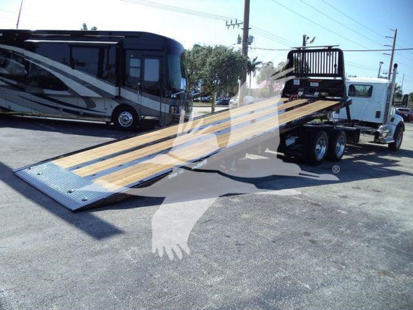 Tow truck flatbed with a black and white Kenworth T880 in background.