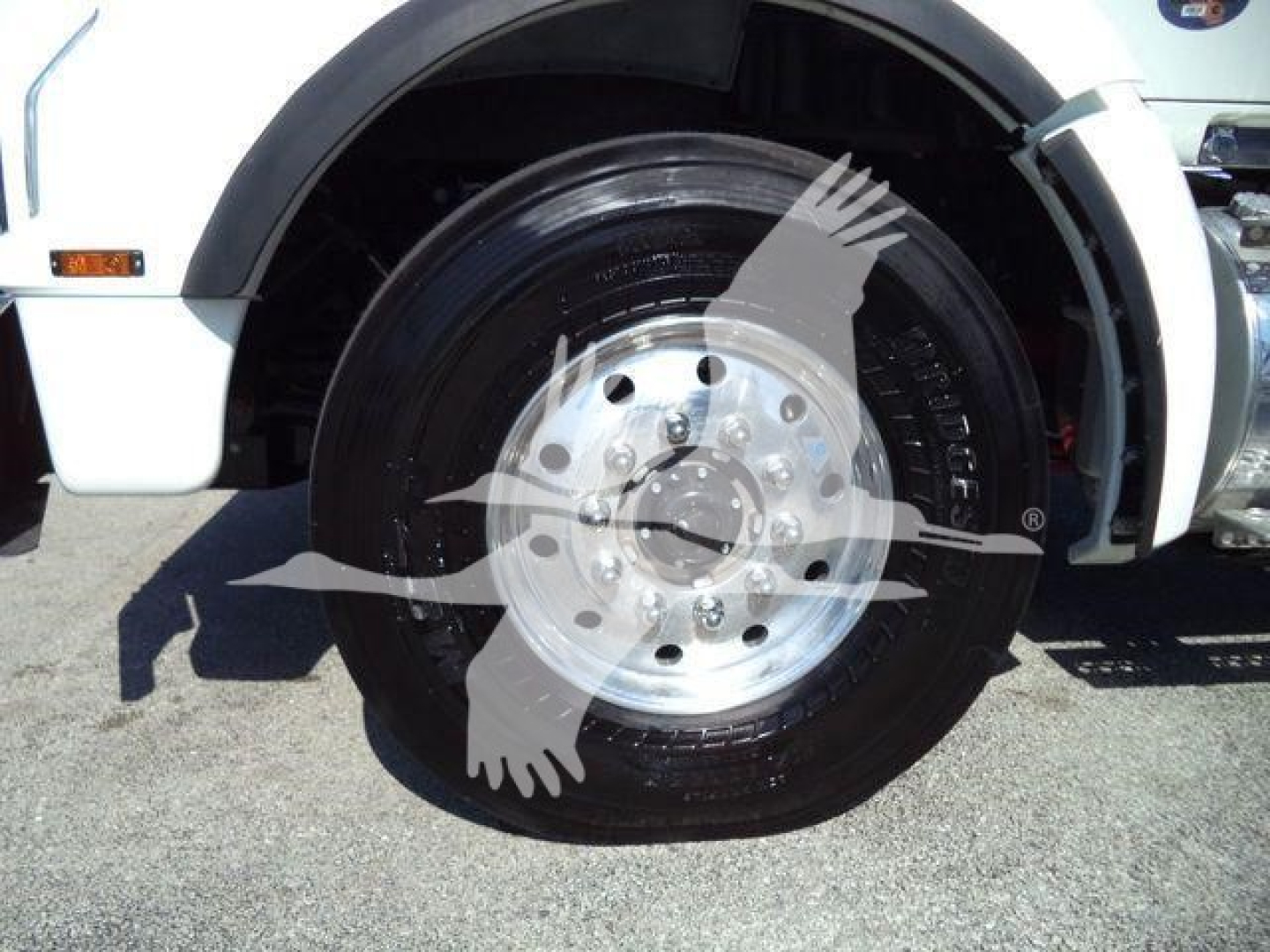 Kenworth T880 front wheel well and tire showing polished aluminum wheel and black tire with white body paneling.