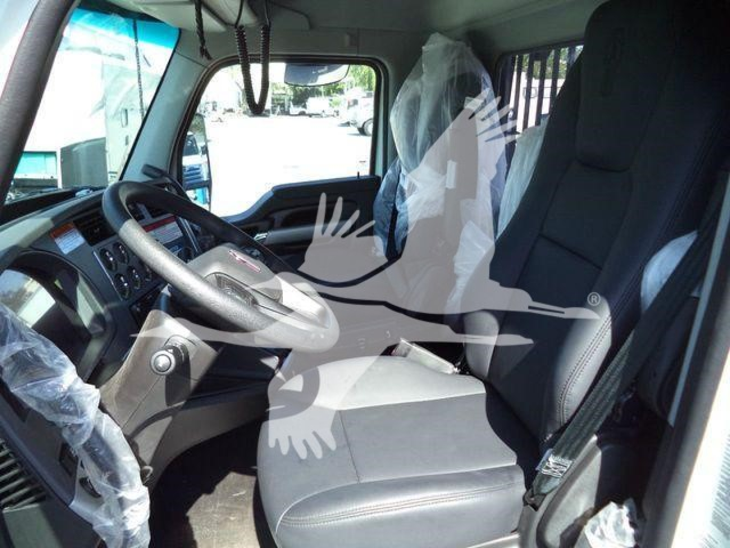 Kenworth T880 cab interior showing steering wheel, driver's seat, and dashboard area with protective plastic on seat and gear