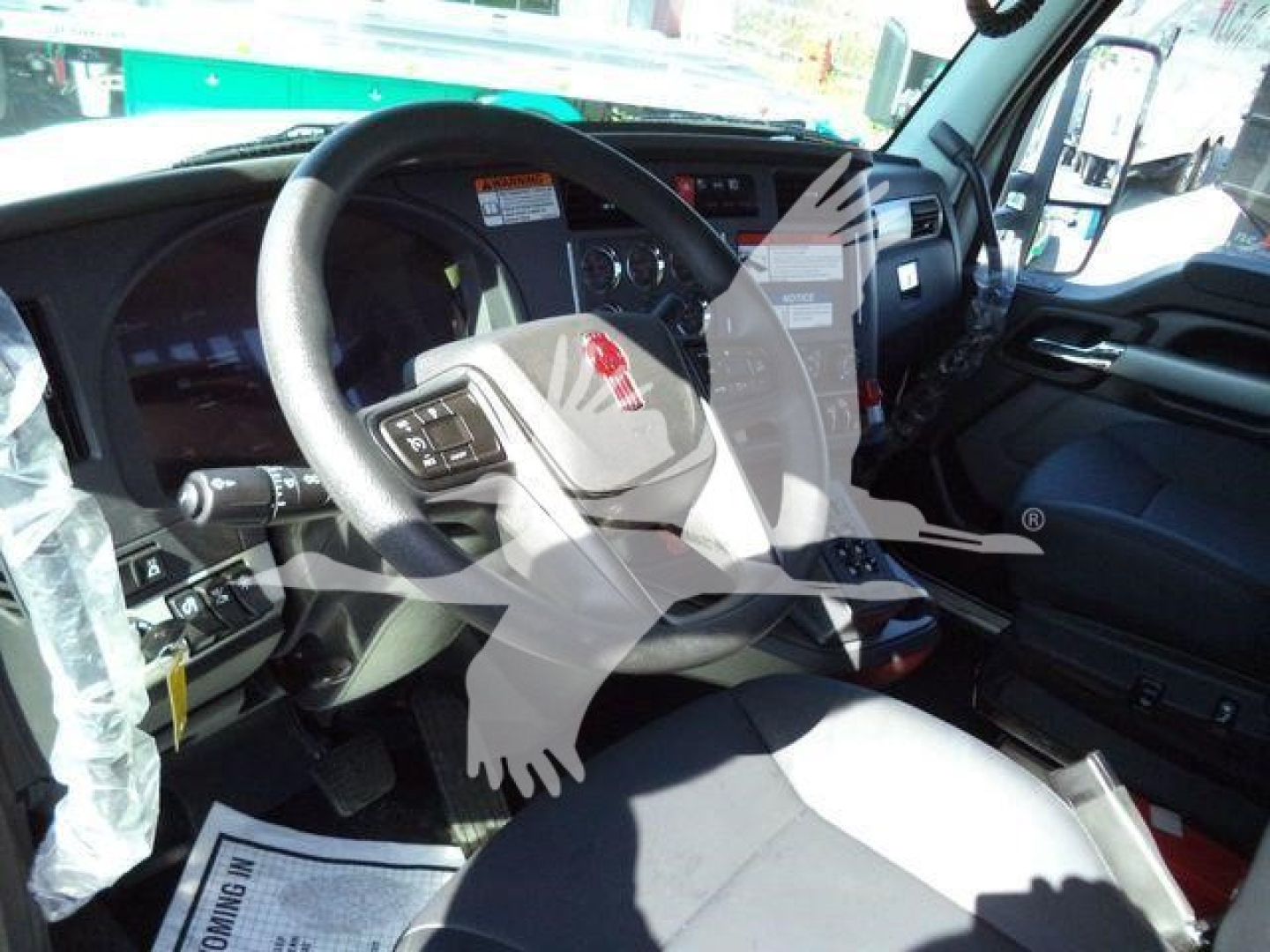 Kenworth T880 truck cab interior showing steering wheel and dashboard area with controls and pedals.