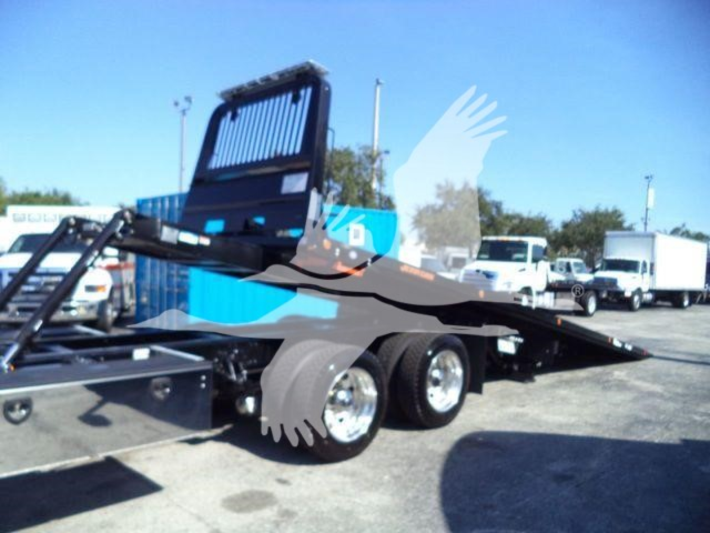Kenworth T880 rollback wrecker chassis showing dual rear wheels and flatbed with loading ramp and hydraulic mechanism, stock image from dealership