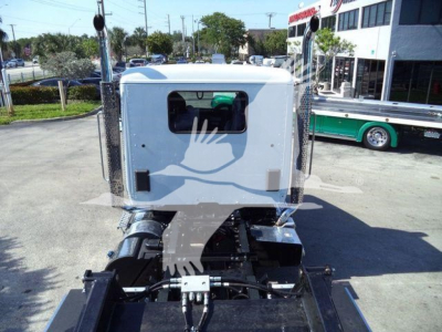 Kenworth T880 cab rear view on rollback truck chassis, white cab with window and chrome exhaust stacks visible.