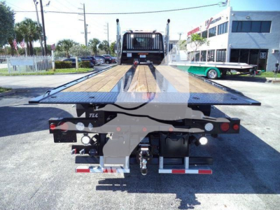 Kenworth T880 rollback truck rear view showing flatbed platform and rear lights with bumper, hitch, and hydraulic components.