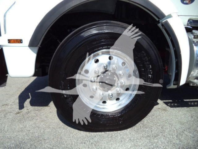 Kenworth T880 front wheel well and tire showing polished aluminum wheel and black tire with white body paneling.