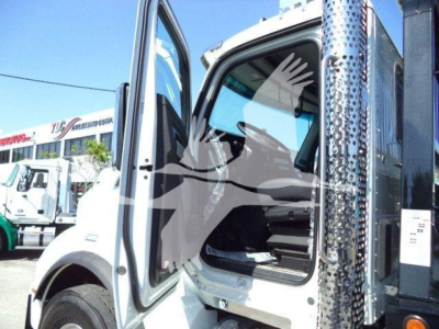 Kenworth T880 truck cab with open door showing interior, side panel with polished metal diamond plate, and other trucks in background.