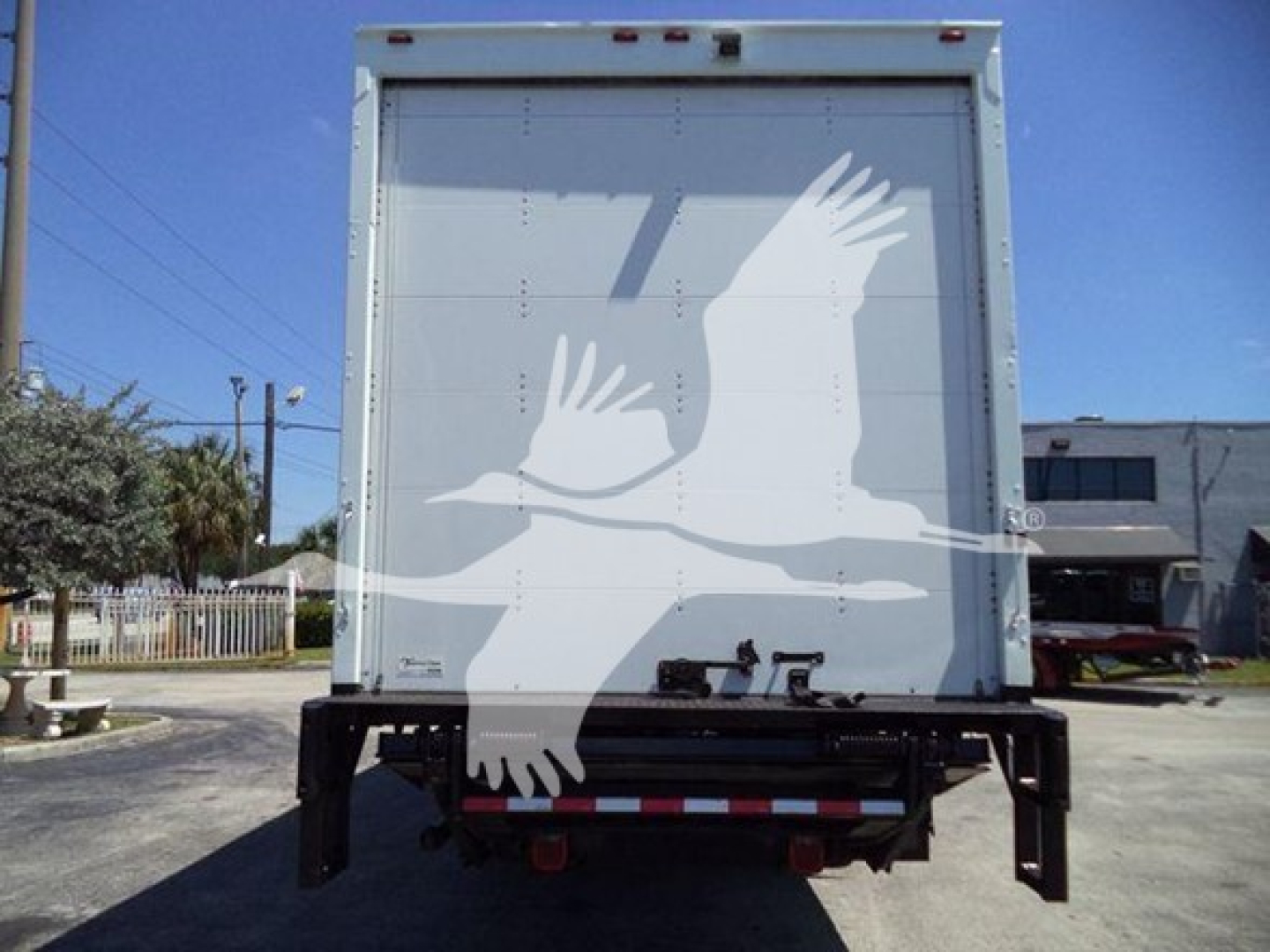 Box truck rear showing cargo area and rear underride guard with white cranes graphic on back door.