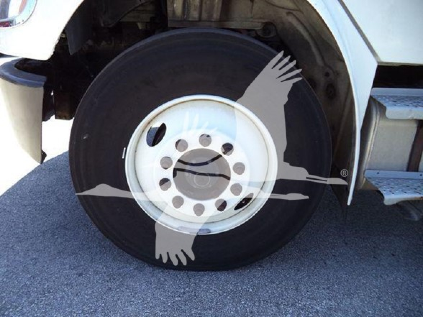Wheel and front section of a Freightliner M2 106 truck showing a single front tire and step area.