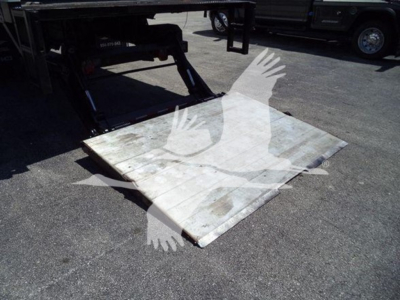 Platform/ramps attached to a Freightliner M2 106 truck with a fold-out steel lift plate showing surface wear.