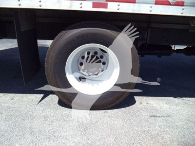 Wheel view of a Freightliner M2 106 truck rear wheel and fender, with partial overlay watermark. No readable model text on tire visible.