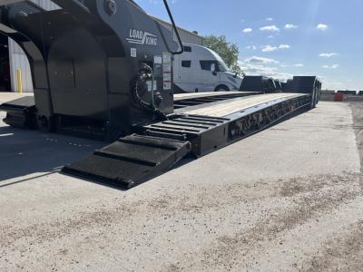 Load King lowboy trailer with hydraulic ramps and long flatbed in service view showing Load King branding
