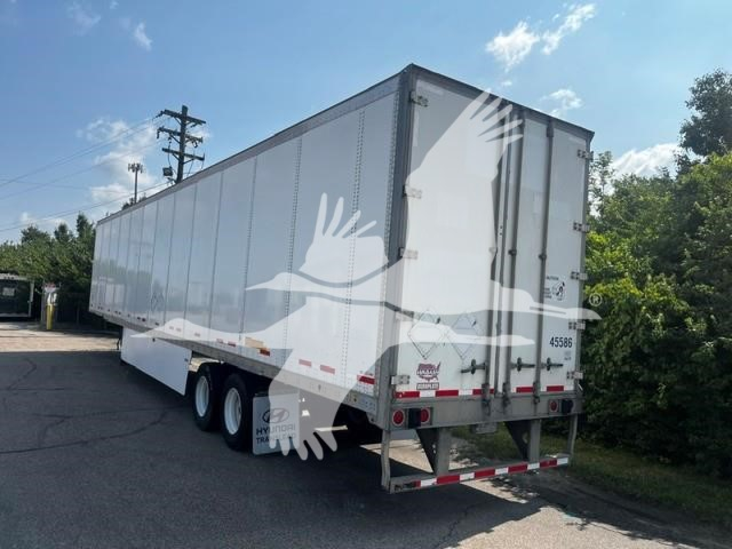 Trailer side and rear showing 2017 Wabash van trailer with triple axle and white body.