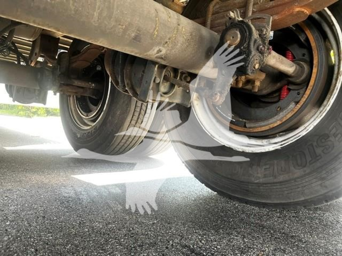 Underbelly view of a 2017 Wabash van trailer showing rear axles, tires, suspension components, and a support bar with a hand watermark overlay; no legible model text visible.