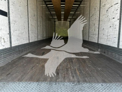 Interior of a 2017 Wabash van trailer with wooden floor, empty cargo area, and metal side walls. Overlaid watermark of birds in flight.