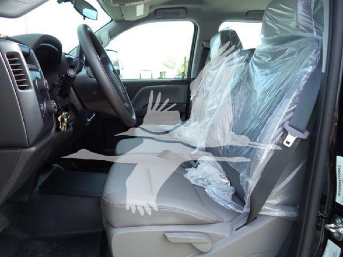 Truck interior with plastic-covered driver and passenger seats, steering wheel, dashboard, and front door in view.