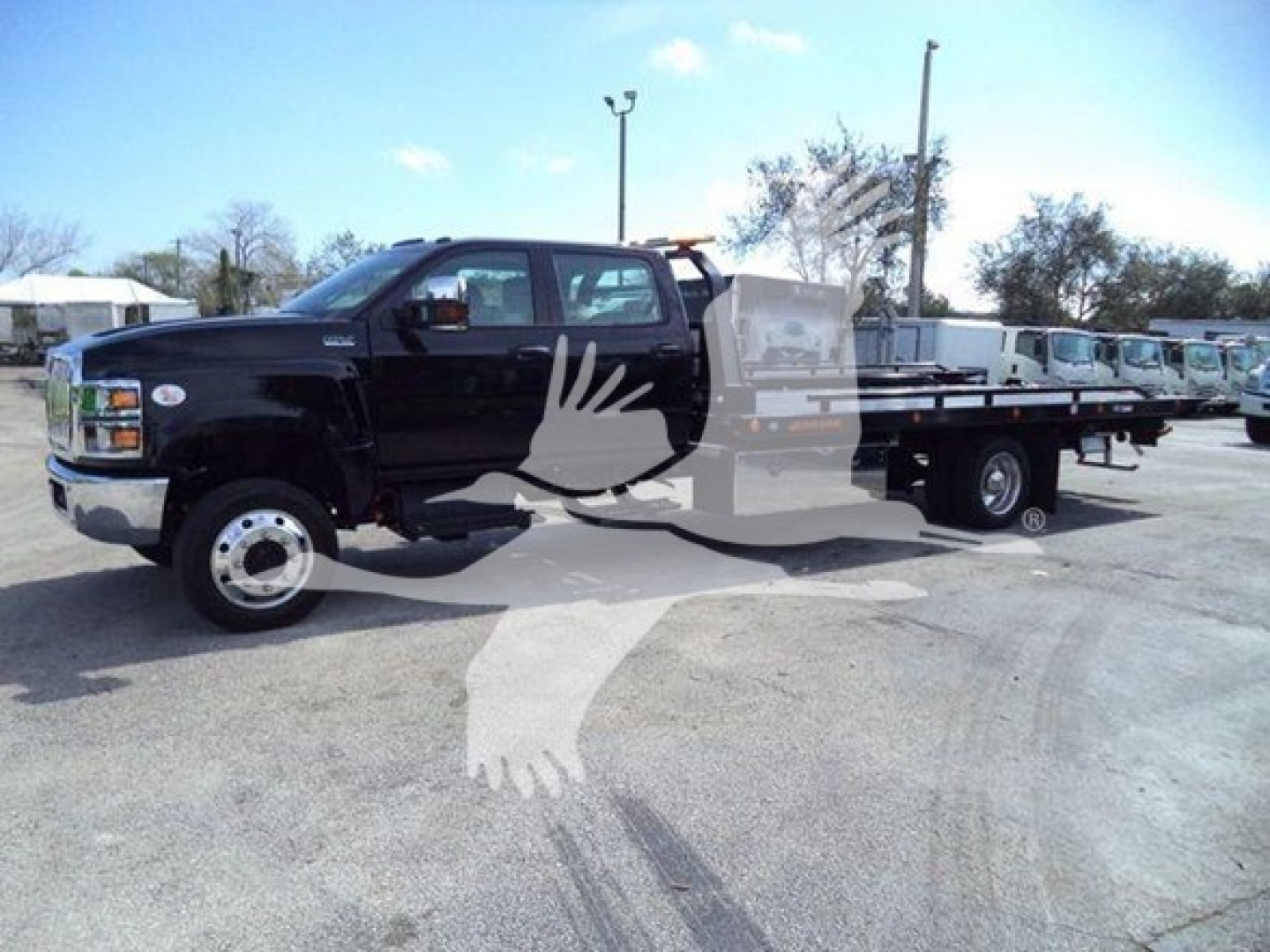 Truck in a dealership lot showing a black 2023 International CV rollback truck with a flatbed and dual rear wheels, VIN 1HTKTSWK3PH419804 visible.