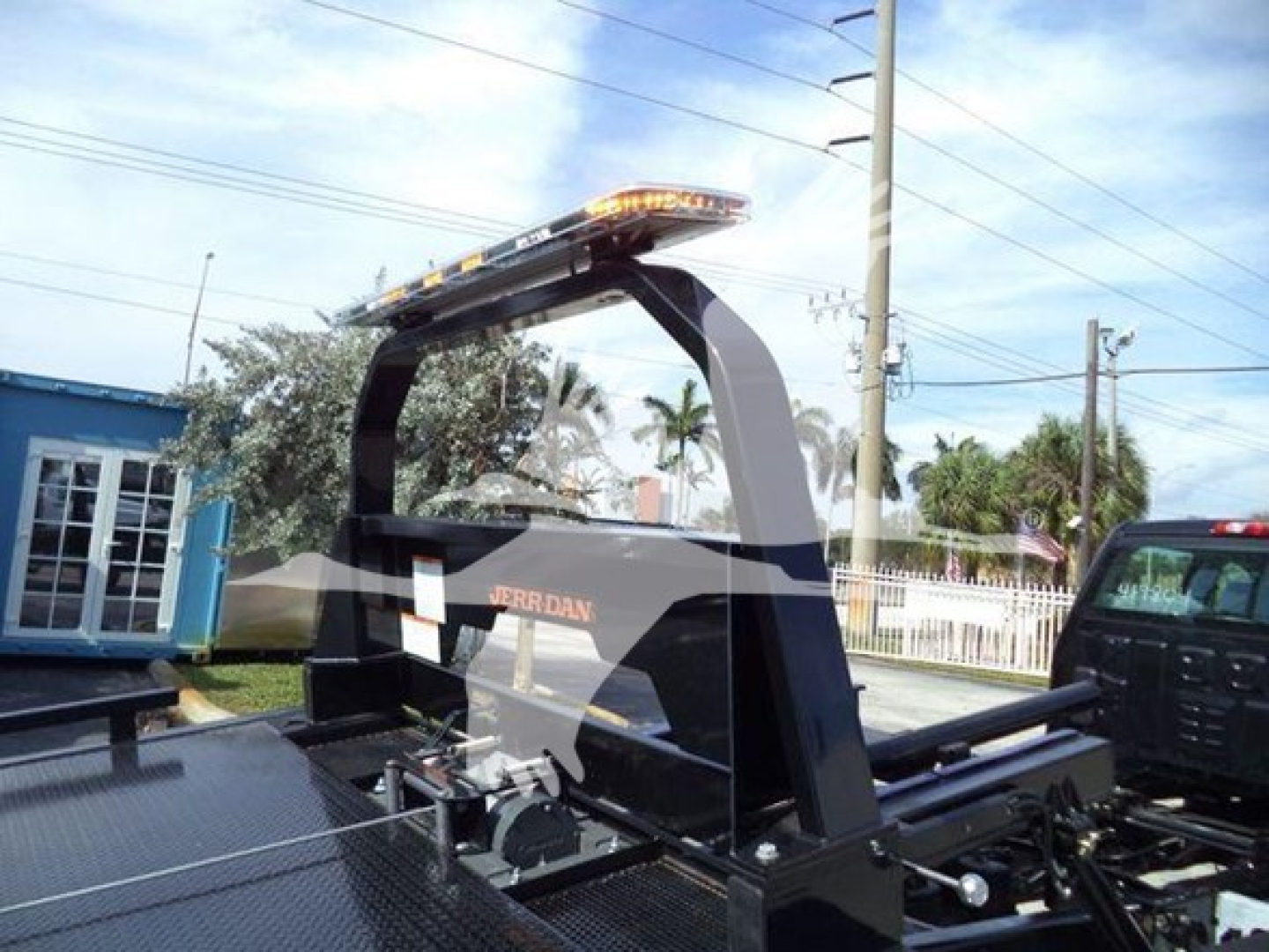 Rollback truck setup showing I-Roll or carrier with orange warning light bar and Jerr-Dan branding on the wheel-lift apparatus.