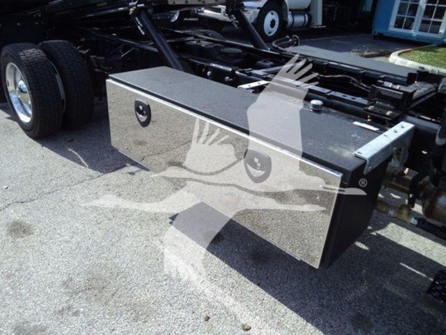 Truck rollback chassis showing a black rectangular aluminum toolbox mounted on the frame.
