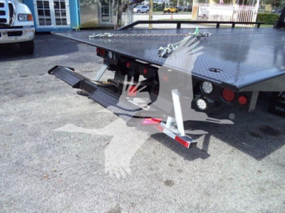 Flatbed tow truck trailer with a folded rear ramp and diamond plate deck, rear lights, and tow hooks visible.
