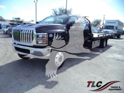 Truck with a flatbed in a dealership lot. Prominent chrome grille and headlights visible.