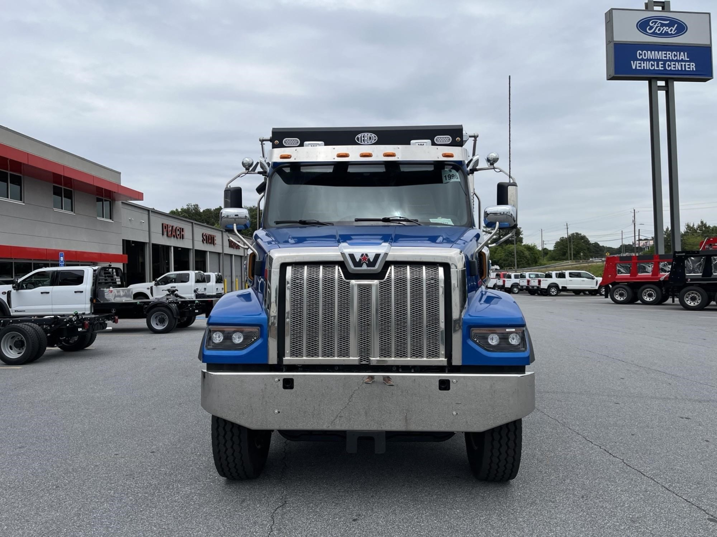 Western Star 47X front view showing chrome grille, blue cab, large bumper, and headlights.