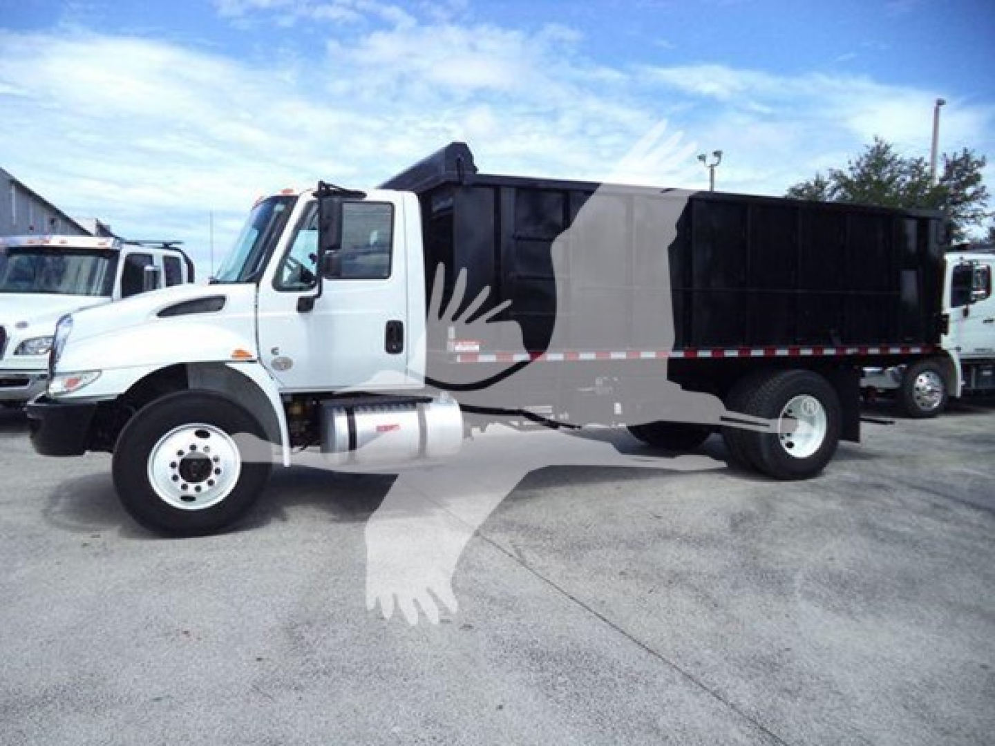 Dump truck showing cab and large black dump body with red/white reflective tape along side.