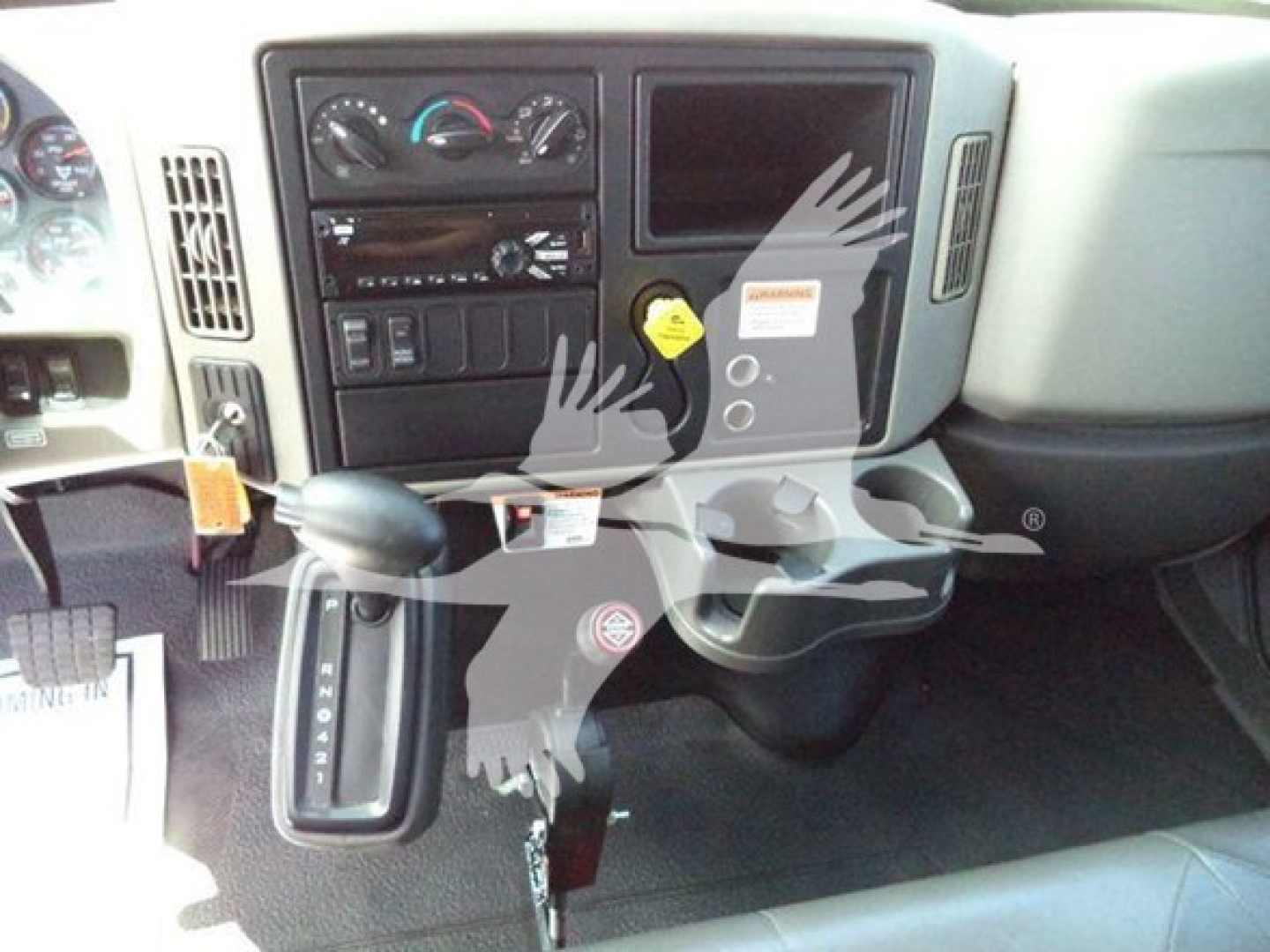 Interior of 2019 International Durastar 4300 dash area showing steering column, gear selector, climate controls, radio, and storage compartment.
